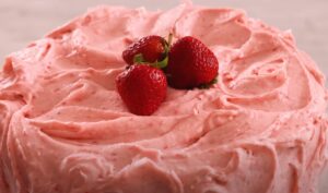 A beautiful strawberry cake, generously frosted in a vibrant pink icing