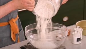 Flour is gently poured into a mixing bowl