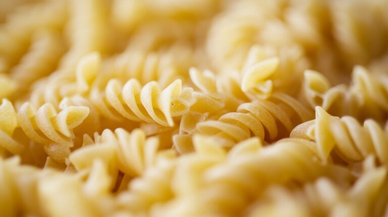 A close-up of uncooked fusilli pasta with a golden hue, highlighting its spiral shape and texture