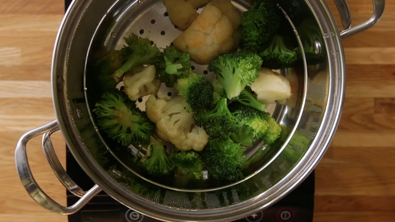 A Steamer with Broccoli and Cauliflower Cooking Inside