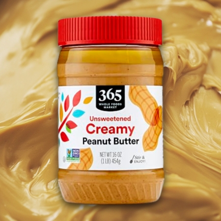 Jar of 365 by Whole Foods Market Unsweetened Creamy Peanut Butter against a peanut butter background