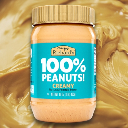 Jar of Crazy Richard’s 100% Peanuts Creamy Natural Peanut Butter against a peanut butter background