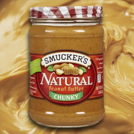 Jar of Smucker’s Natural Chunky Peanut Butter with a peanut butter background
