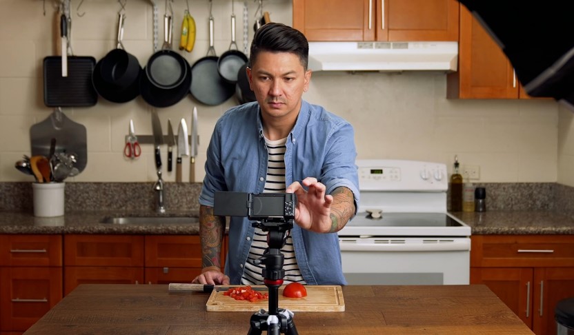 Man setups camera on a tripod before starting a cooking session