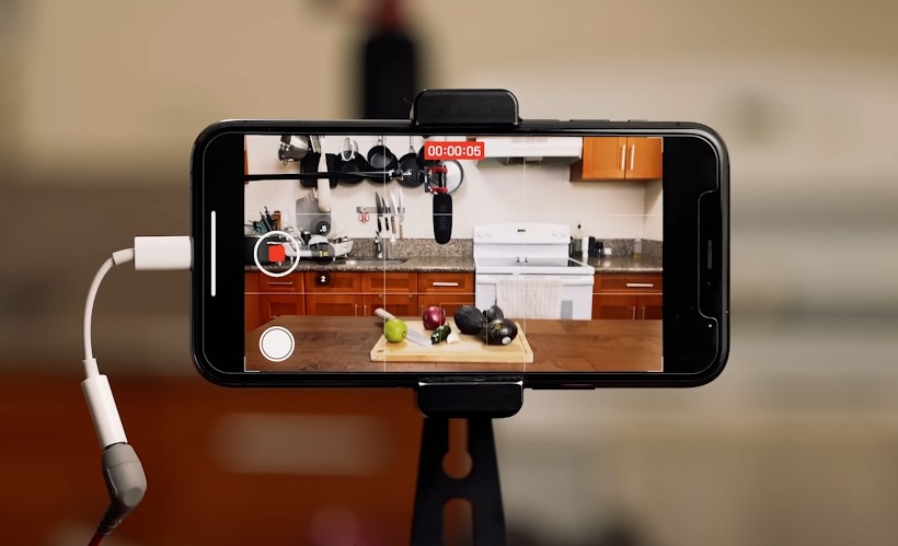 Smartphone capturing a cooking tutorial with fresh ingredients on a wooden cutting board