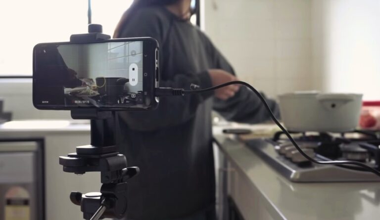Close-up of a phone on a tripod recording a person cooking