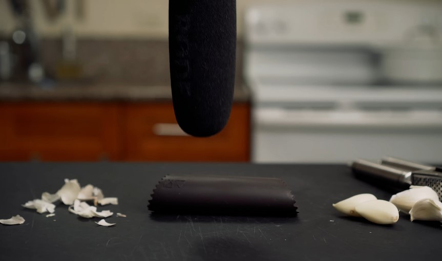 Garlic cloves and husks on a dark surface, with a microphone overhead