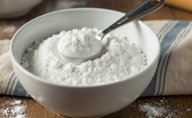 A bowl of flour with a wooden spoon resting on top