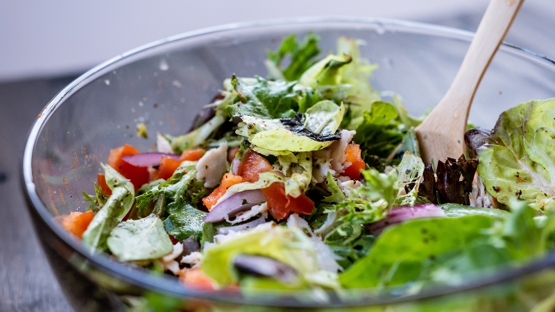 A fresh salad in a glass bowl highlights the potential risks of a high fiber diet when eaten in excess
