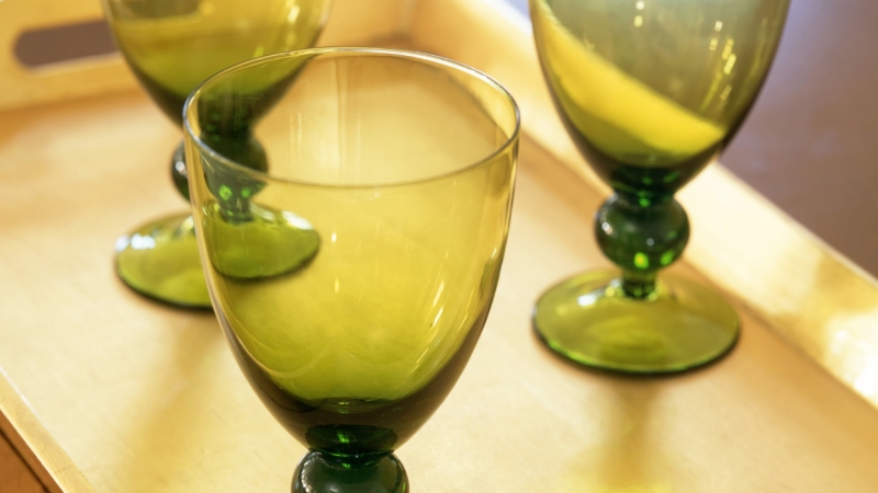 Green dessert glasses with stems placed on a wooden tray, ready for serving