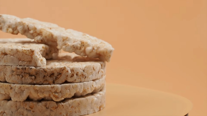 Stack of plain rice cakes on a beige surface against an orange background