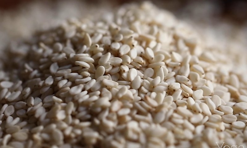 Close-up of a mound of white sesame seeds, displaying their smooth texture and oval shape
