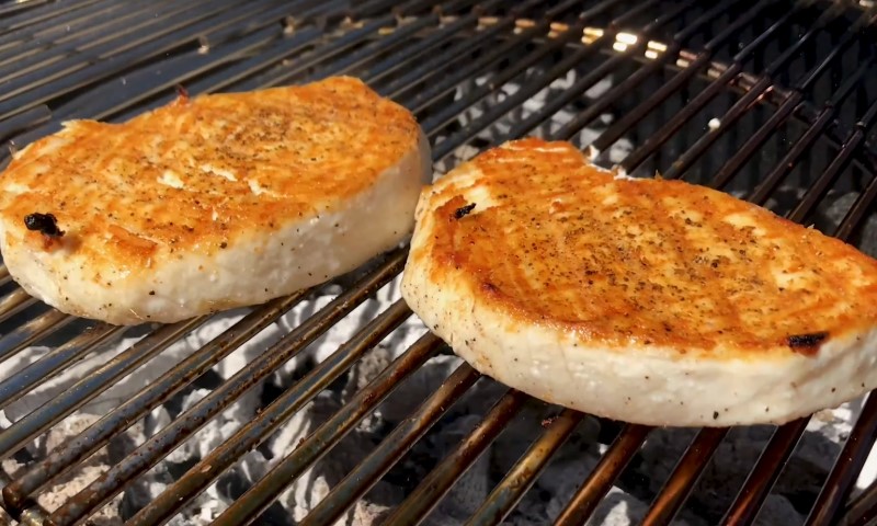 Two swordfish chops sizzling on a grill