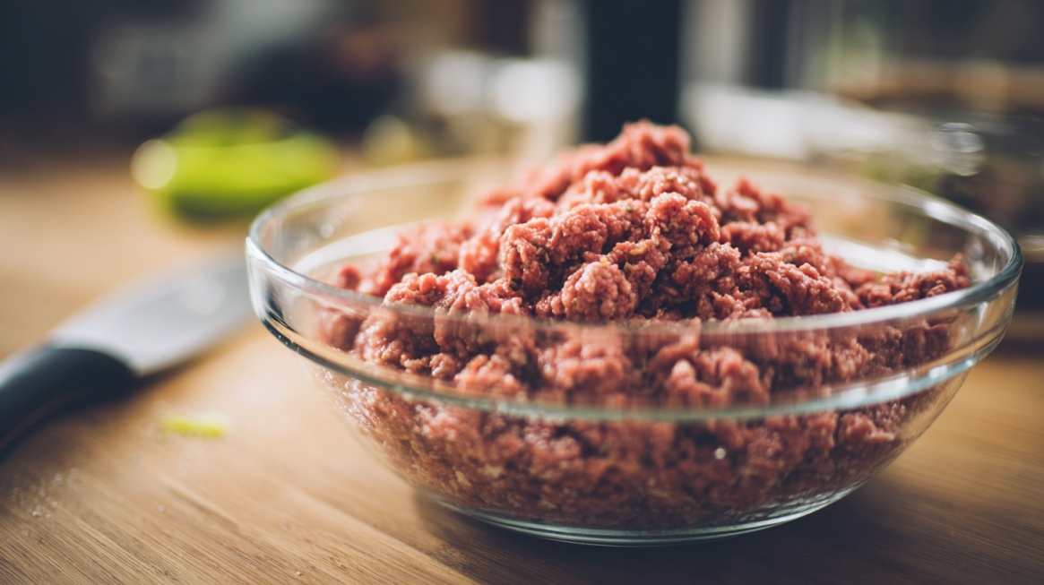 Raw ground beef in a glass bowl on a kitchen counter