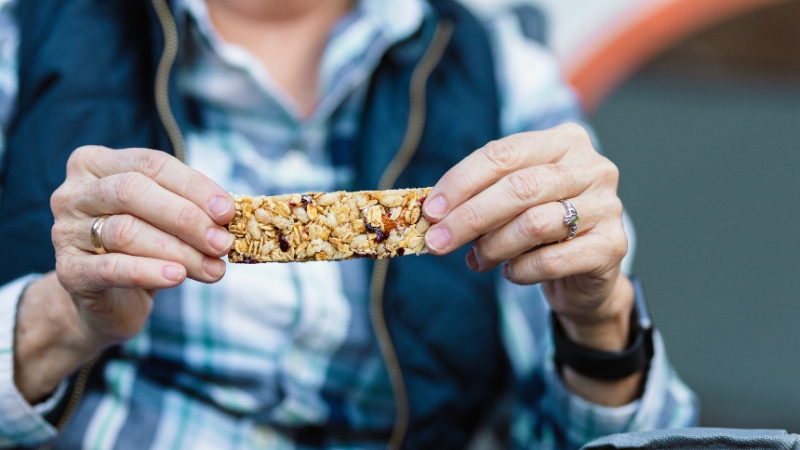 Person holding a protein bar made with oats and dried fruit