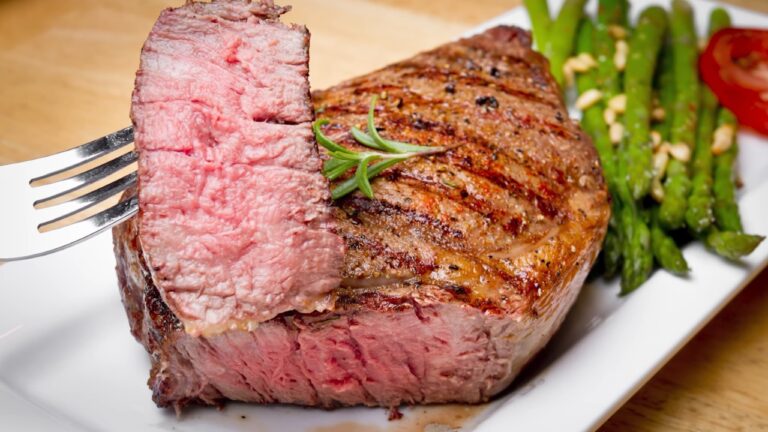 Sliced steak showing a pink center next to a whole grilled piece with asparagus