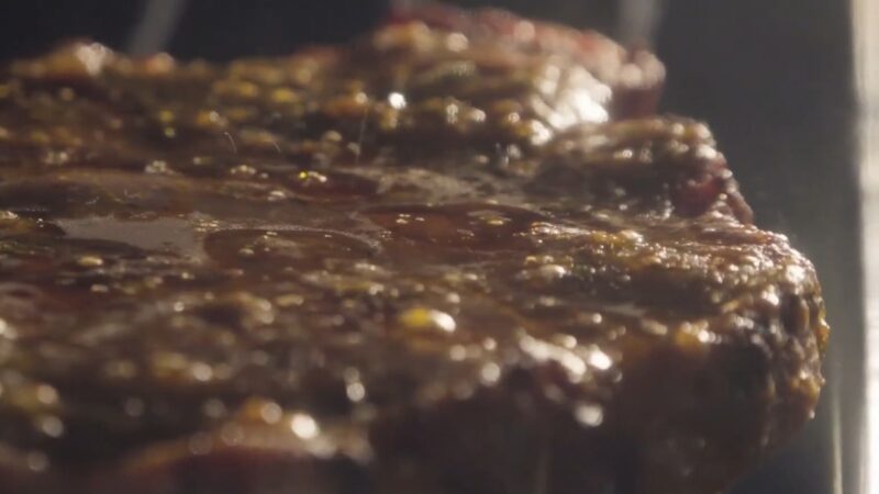 Steak in oven with juices on the surface and a browned crust
